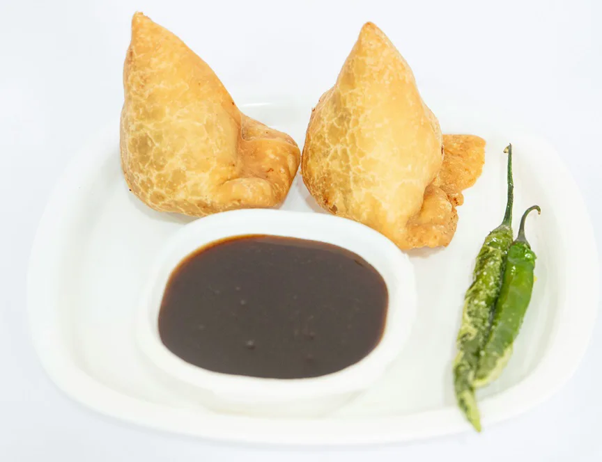 Two Samosa on a plate with chutney - Indian Street Foods