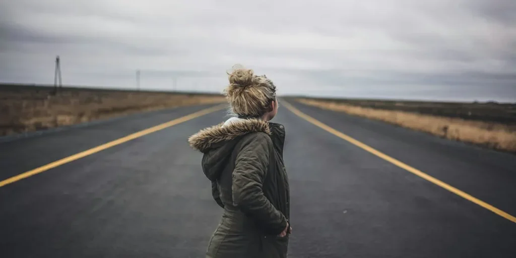 5 Tips for Women Traveling Alone Over 50 - A woman standing in the middle of the road