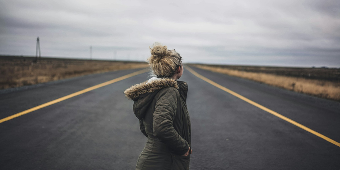 5 Tips for Women Traveling Alone Over 50 - A woman standing on the road