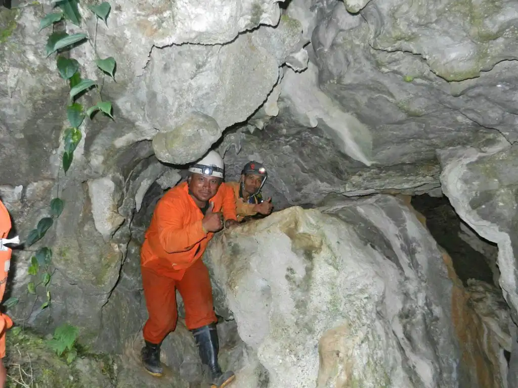 Team members crawling and posing inside the Krem Mawmluh Cave in Meghalaya