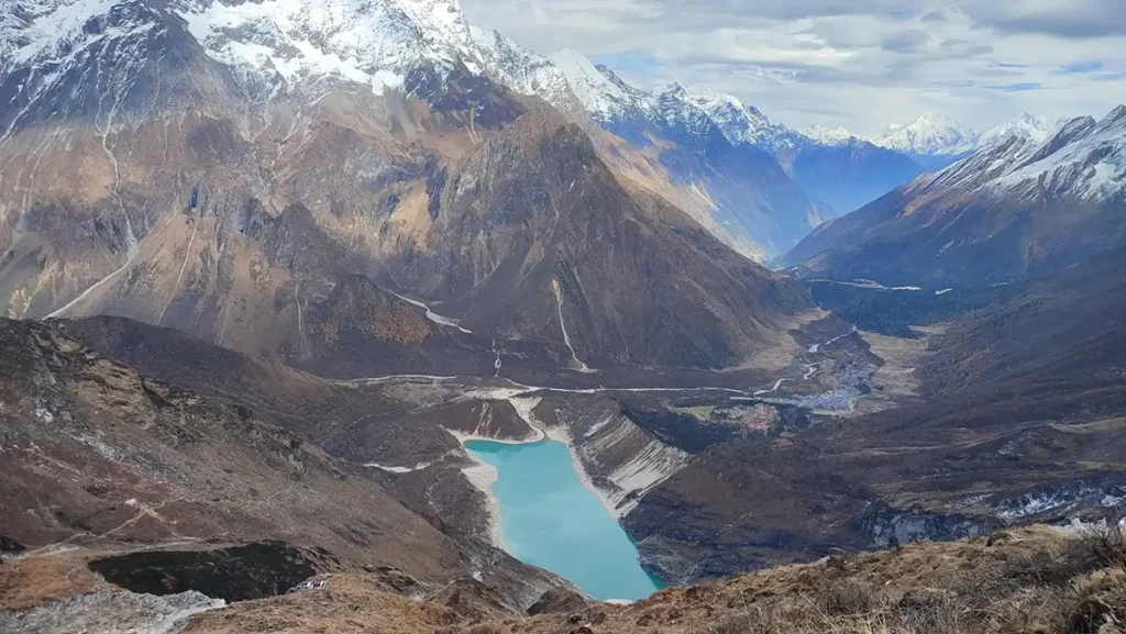 manaslu circuit trek photos with a turqoiuse lake, snow capped mountain peaks and a valley trekking in Nepal